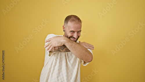 Young man smiling confident hugging himself over isolated yellow background photo