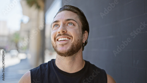 Young hispanic man smiling confident looking to the sky at street photo