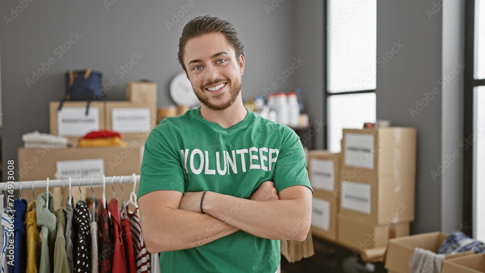Young hispanic man volunteer standing with arms crossed gesture smiling at charity center Young hispanic man volunteer standing with arms crossed gesture smiling at charity center