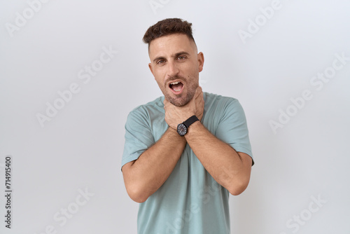 Hispanic man with beard standing over white background shouting suffocate because painful strangle. health problem. asphyxiate and suicide concept.
