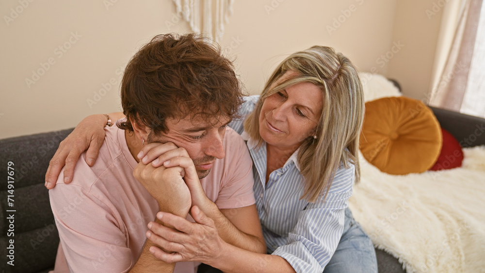 Mother and son share supportive hug, sitting on sofa at home, family tackles sadness and anxiety together Mother and son share supportive hug, sitting on sofa at home, family tackles sadness and anxiety together