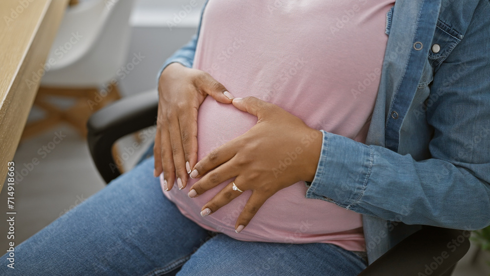 Fototapeta premium Heartwarming moment, young successful pregnant businesswoman at office, forming a heart gesture with her hands over belly, embracing upcoming motherhood indoors