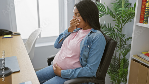 Serious young pregnant businesswoman touching belly, suffering nausea indoors at office
