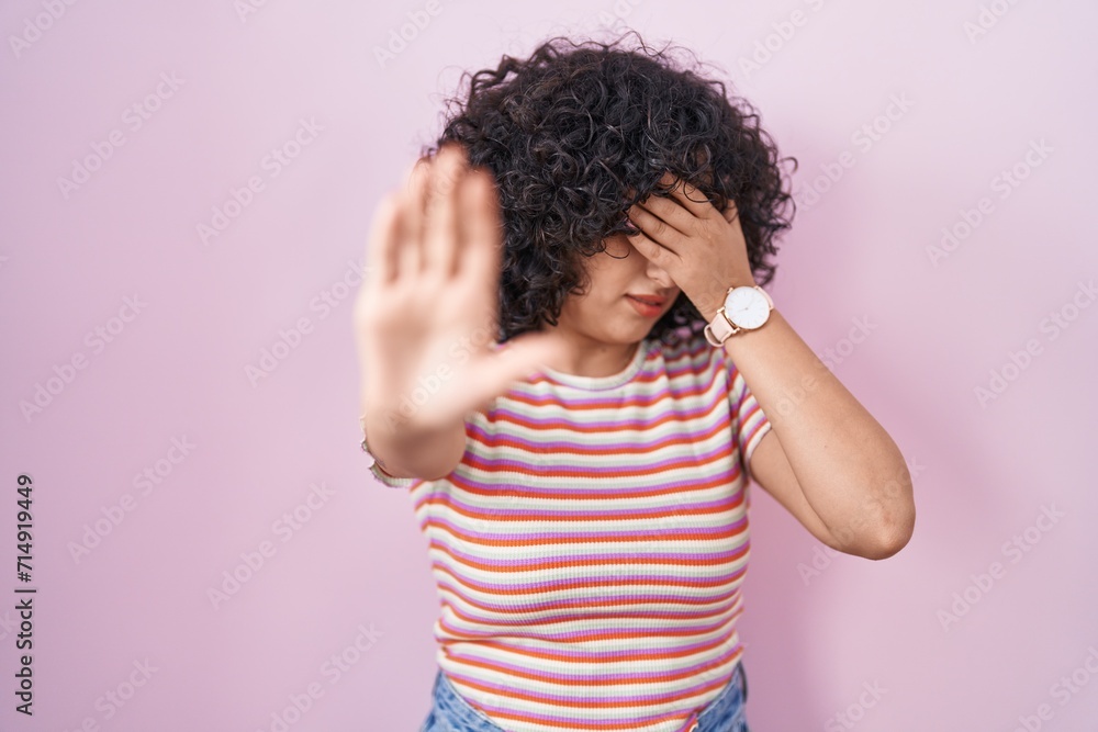 Young middle east woman standing over pink background covering eyes with hands and doing stop gesture with sad and fear expression. embarrassed and negative concept. Young middle east woman standing over pink background covering eyes with hands and doing stop gesture with sad and fear expression. embarrassed and negative concept.