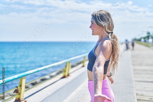 Young blonde woman wearing sportswear breathing at seaside