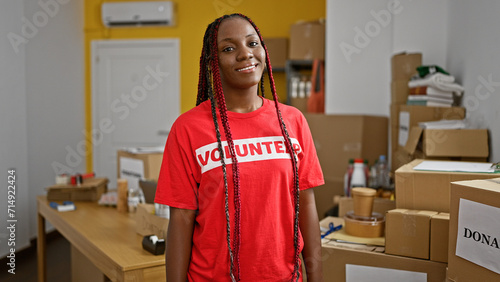 Smiling african american woman confidently standing, volunteering at charity center, epitome of beautiful community support