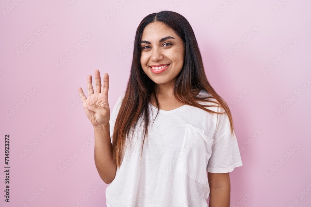 Young arab woman standing over pink background showing and pointing up with fingers number four while smiling confident and happy. Young arab woman standing over pink background showing and pointing up with fingers number four while smiling confident and happy.
