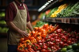 Midsection of male worker holding bell peppers at grocery store counter in supermarket