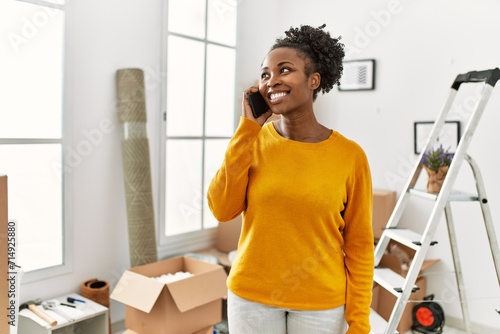 African american woman talking on smartphone standing at new home