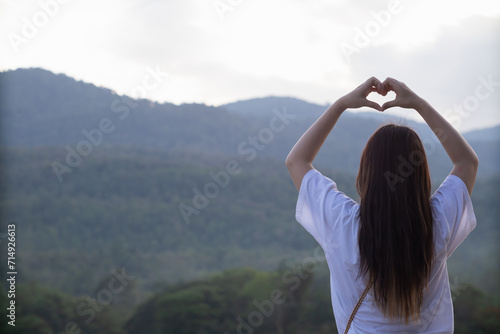 woman raised her hands and made heart symbol to express meaning of love friendship and kindness to her friends and lovers. woman uses her hands to make a heart symbol that means love and friendship. © thatinchan