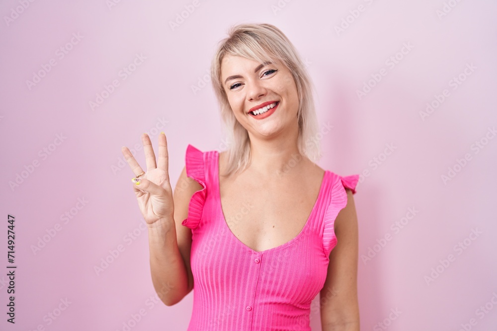 Young caucasian woman standing over pink background showing and pointing up with fingers number three while smiling confident and happy. Young caucasian woman standing over pink background showing and pointing up with fingers number three while smiling confident and happy.