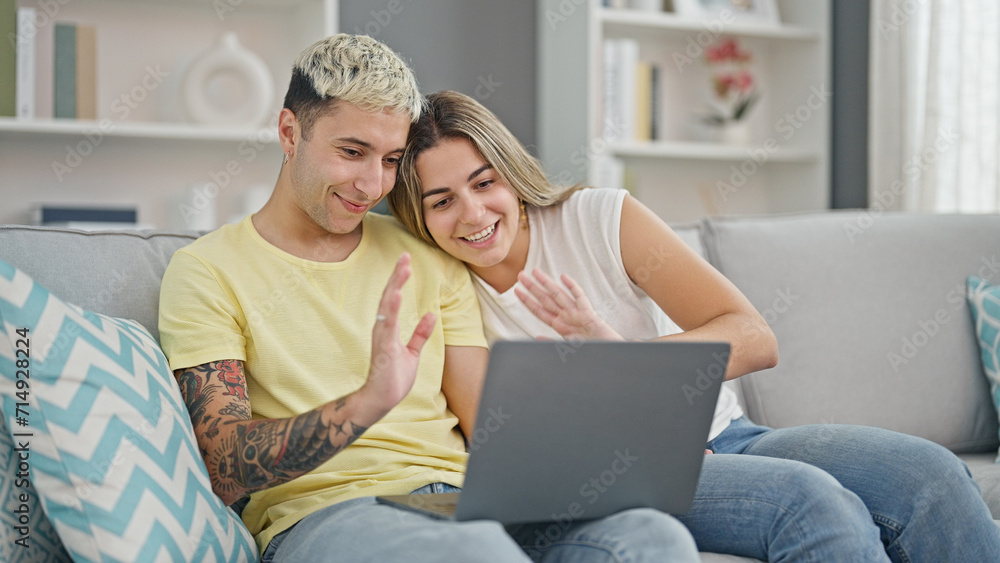 Beautiful couple having video call sitting on sofa smiling at home Beautiful couple having video call sitting on sofa smiling at home