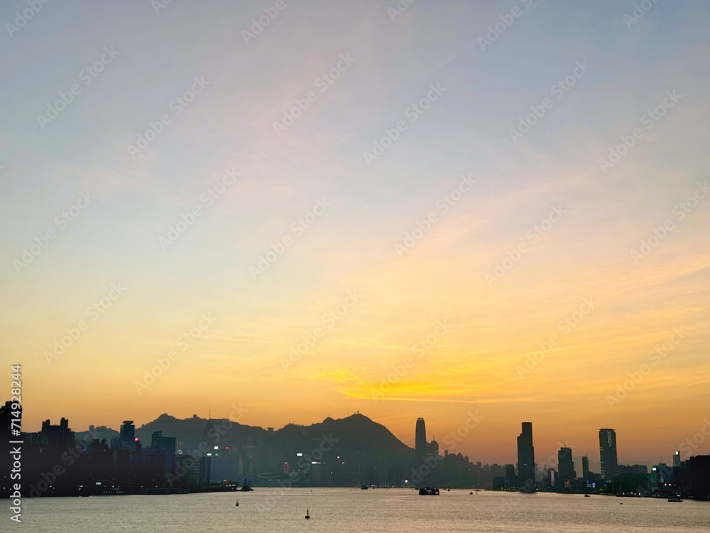 Fototapeta premium Maginificent Hong Kong evening skyline with romantic sunset view from Kai Tak Cruise Ferry Terminal Park, rooftop level, seeing the ferries, harbour, strait, and Hong Kong skyscrapers