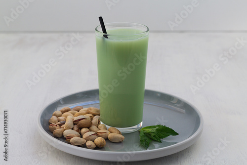 smoothie with nuts. Alternative milk. glass of Natural plant based Pistachio milk with pistachionuts and green mint on the white table. A paper straw in a glass. Healthy diet. copy space photo