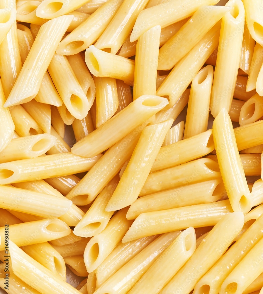 Close-up view of uncooked penne pasta arranged densely to fill the entire frame. Close-up view of uncooked penne pasta arranged densely to fill the entire frame.
