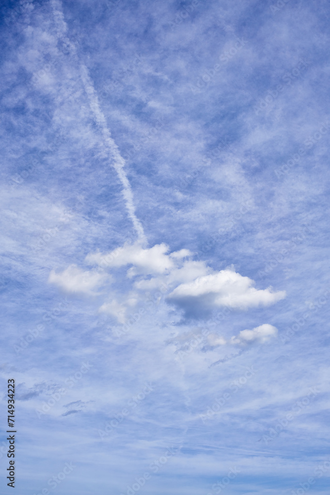 Expansive blue sky with white clouds and visible contrail creating a serene backdrop. Expansive blue sky with white clouds and visible contrail creating a serene backdrop.