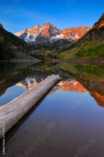A log on Maroon Lake below the dawn-lit Maroon Bells, Aspen, Colorado, USA.