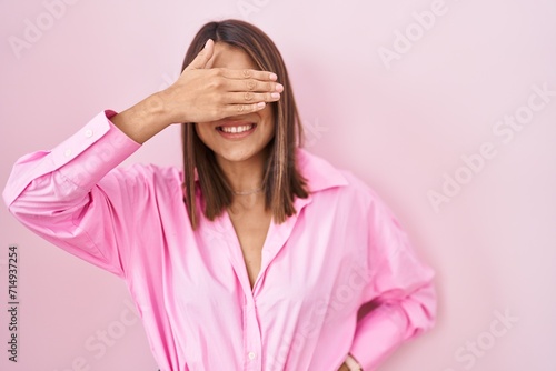 Young hispanic woman wearing glasses standing over pink background smiling and laughing with hand on face covering eyes for surprise. blind concept. © Krakenimages.com