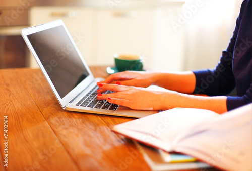 Crop woman using laptop working at home