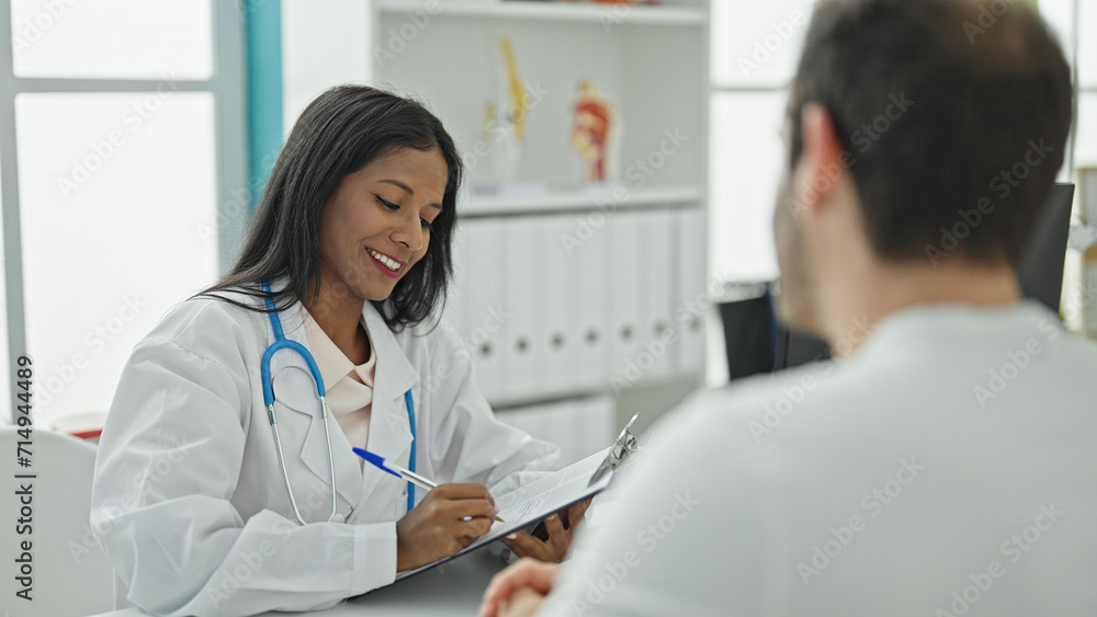 Doctor and patient sitting on table writing medical report at the clinic Doctor and patient sitting on table writing medical report at the clinic