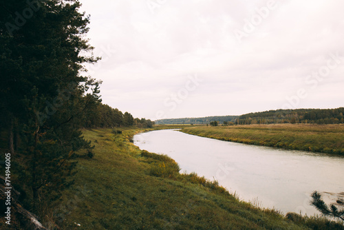 The landscape of the river with green banks. Autumn forest along the river. The river cuts through the fields. Beautiful river banks.
