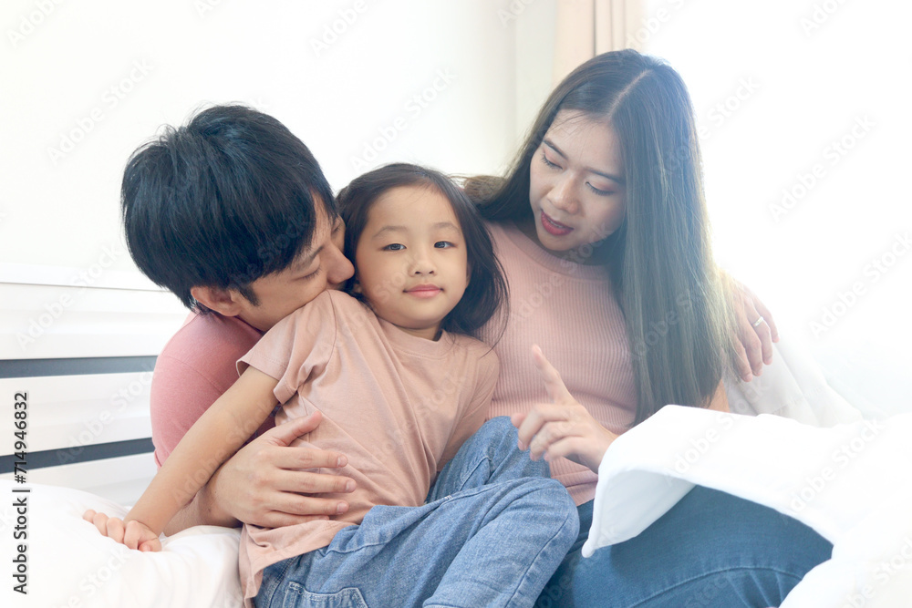 Happy Asian family having fun in bedroom. Father, mother and daughter playing together during lying on white bed. Parents having good memory with kid child girl at home. parenthood and childhood