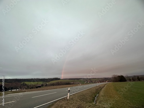 Schöner Regenbogen, im Vordergrund eine wenig befahrene Straße