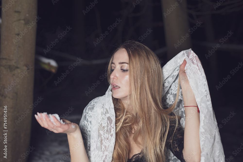 Fototapeta premium young blond woman with blue eyes dancing in the dark night of an very cold snow winter