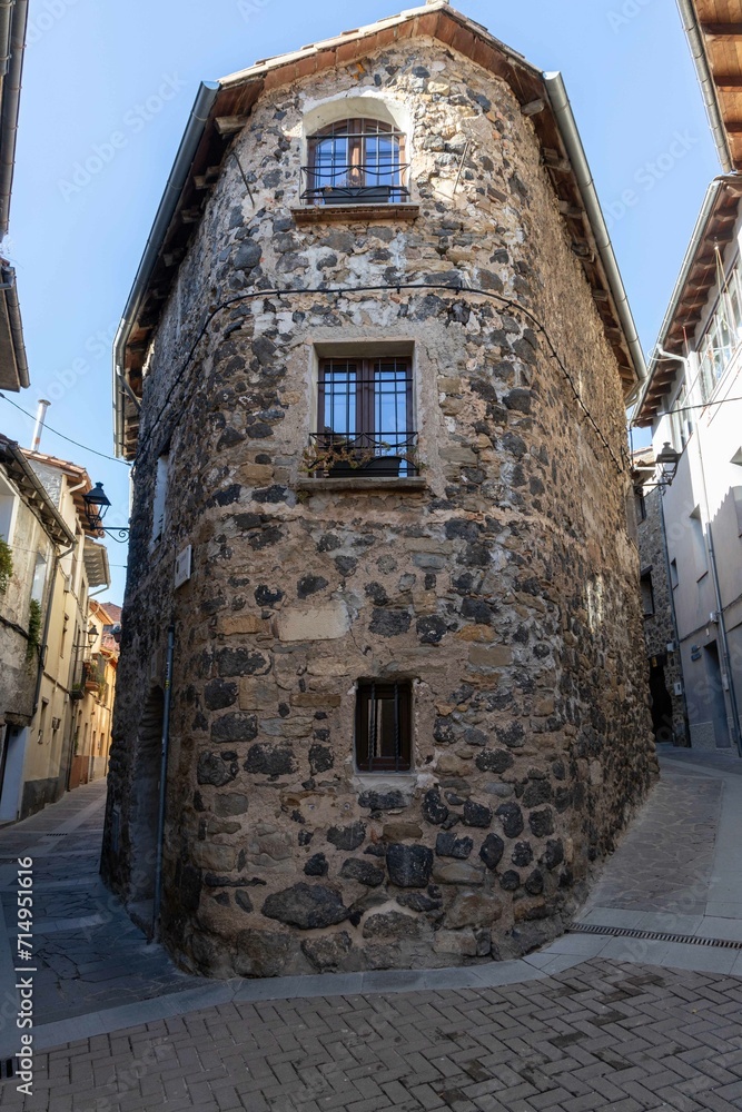 A unique corner building made of stone stands at the junction of two narrow streets in Olat town, Catalonia, Spain