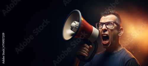 An intense man with glasses shouts loudly into a megaphone, creating a burst of light and energy against a dark backdrop with copy space. photo