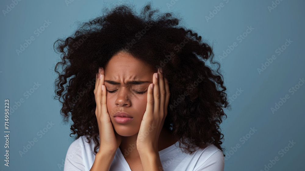 young woman suffering from headache on grey background.