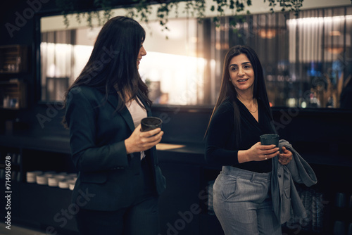 Smiling businesswomen talking over coffee while walking in a hotel lobby photo