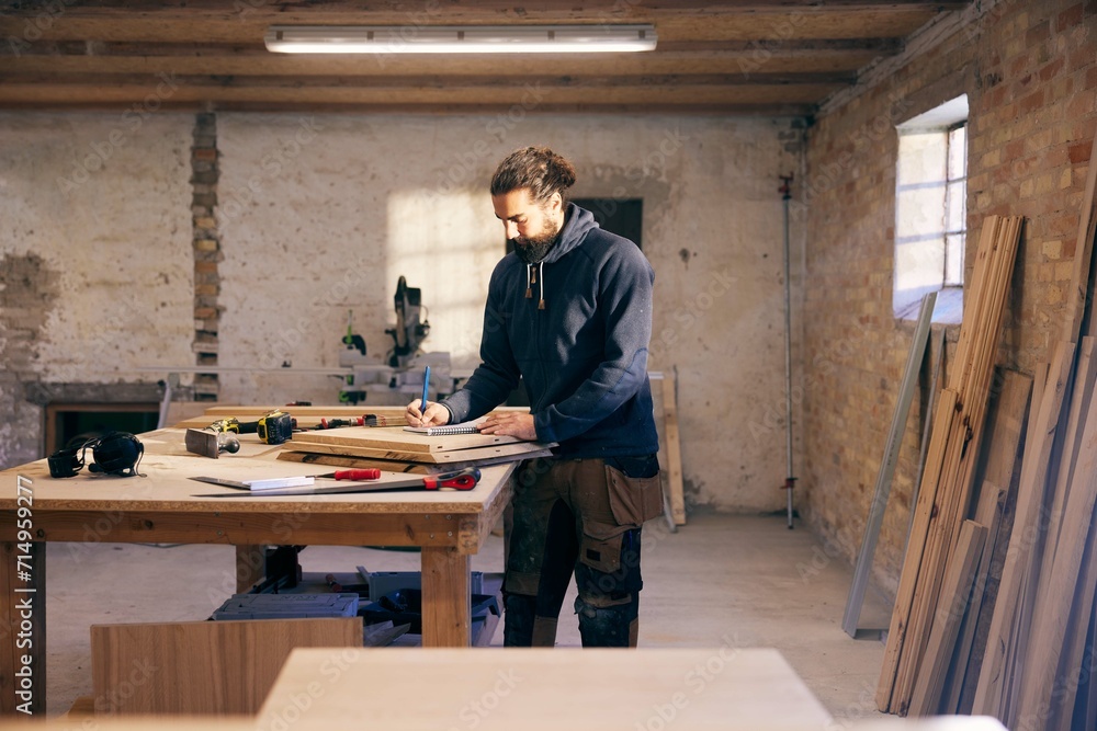 Carpenter working on a design at a workshop bench Carpenter working on a design at a workshop bench
