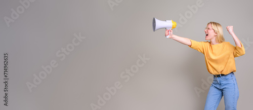 Furious female activist gesturing and screaming over megaphone while standing on white background