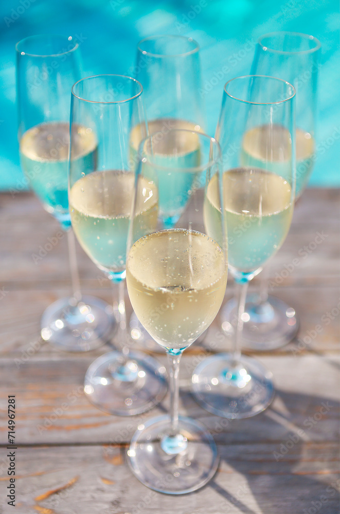 Champagne glasses on wooden background near pool Champagne glasses on wooden background near pool