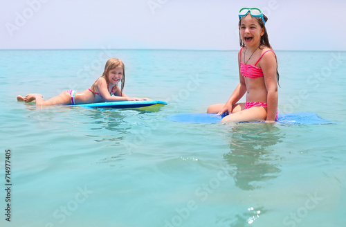 Little girls with surfing boards playing on tropical ocean beach. Summer water fun for surfer kids