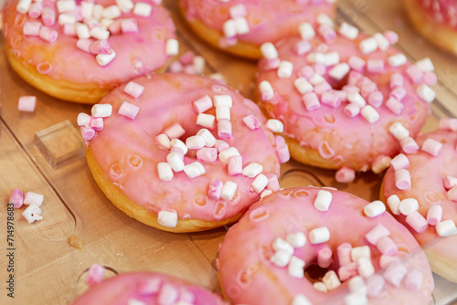 A lot of donuts with pink icing on the counter in a store. Traditional mouth-watering sweets. Close-up.