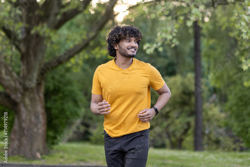 Smiling young Indian man running in the park, doing a morning jog and exercise