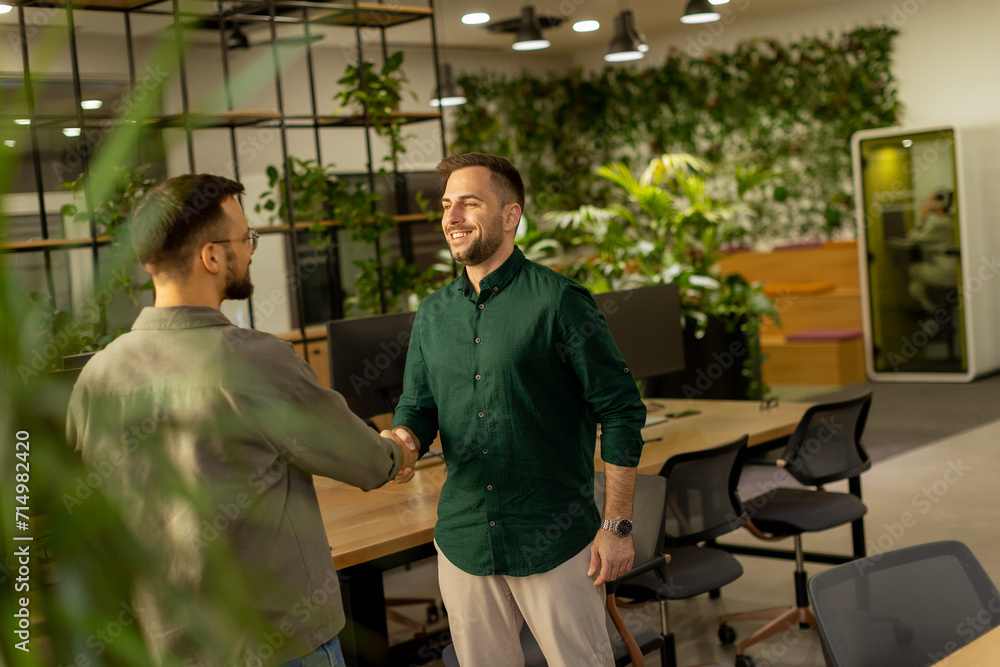 Friendly Handshake Between Colleagues in a Modern Office at Dusk Friendly Handshake Between Colleagues in a Modern Office at Dusk