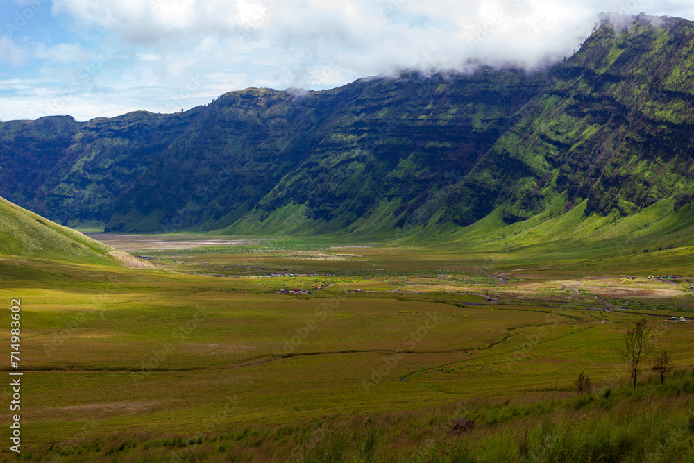Landscape of green hills in the mountains on a cloudy day. Location of Mount Bromo in Bromo Tengger Semeru National Park, East Java, Indonesia Landscape of green hills in the mountains on a cloudy day. Location of Mount Bromo in Bromo Tengger Semeru National Park, East Java, Indonesia
