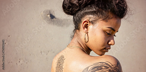 ritratto primo piano profilo di giovane donna di colore, elegante e raffinata acconcciatura, orecchino, tatuaggi photo