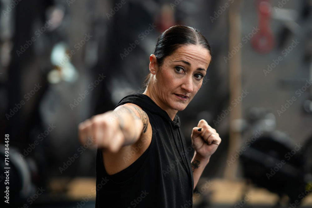 Female boxer throwing a jab while shadowboxing in the gym - obrazy, fototapety, plakaty 