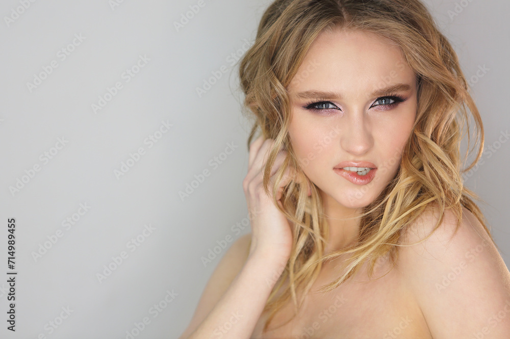 Young beautiful woman with blonde curly hair on grey background Young beautiful woman with blonde curly hair on grey background