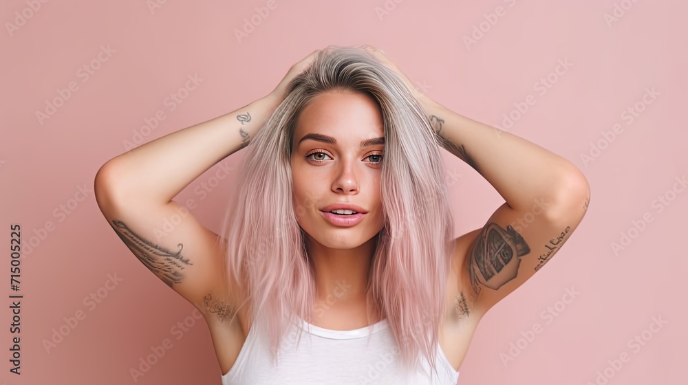 Fototapeta premium Portrait of a pleasant-looking casual woman with long hair, pink tips, tattoos on her arms, dressed in a white casual t-shirt.