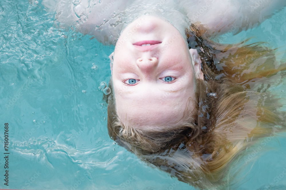 Boy with long blonde hair swimming in resort swimming pool on vacation Boy with long blonde hair swimming in resort swimming pool on vacation