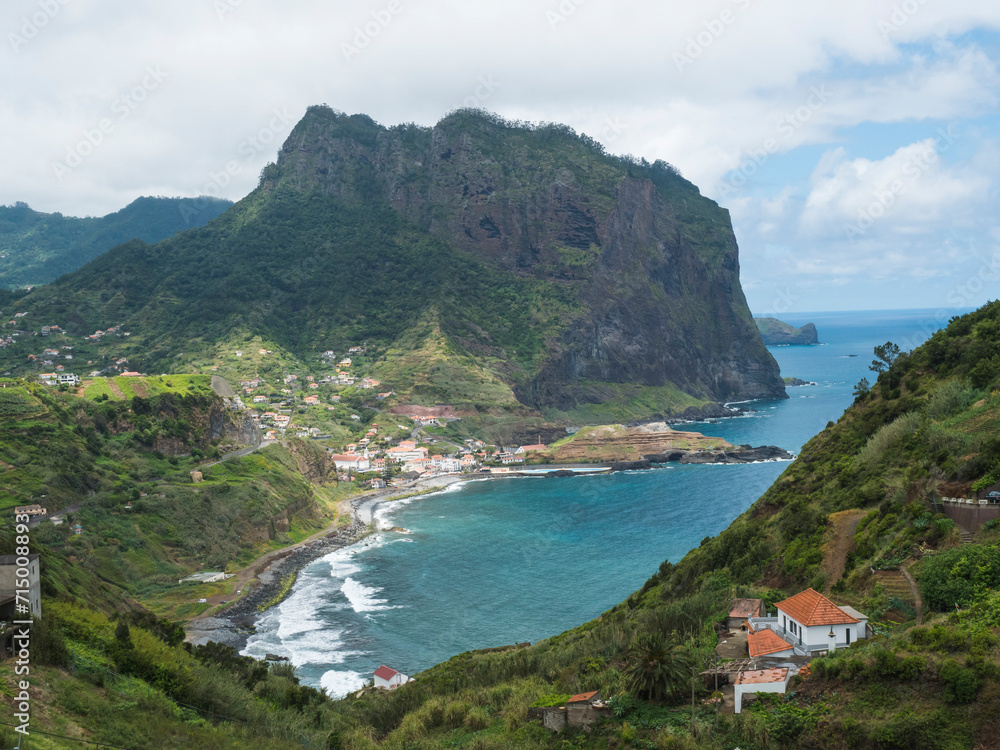 Aerial view of Porto da Cruz town with green cliff of Penha D'Aguia mountain and beautiful coast. Landscape scenery at the north of Madeira island, Portugal