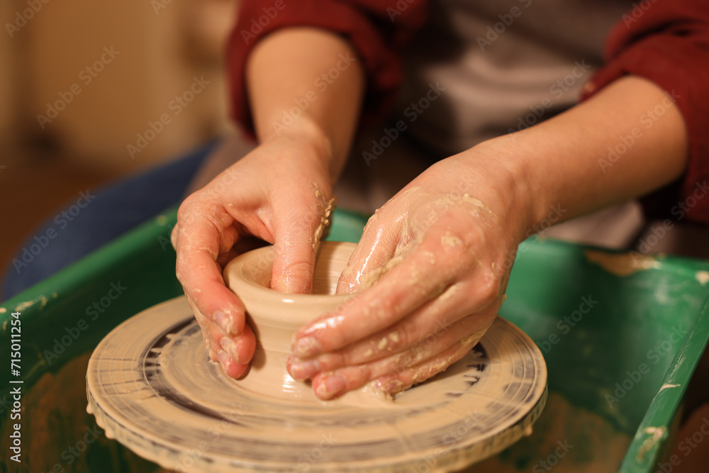 Woman crafting with clay on potter's wheel indoors, closeup Woman crafting with clay on potter's wheel indoors, closeup