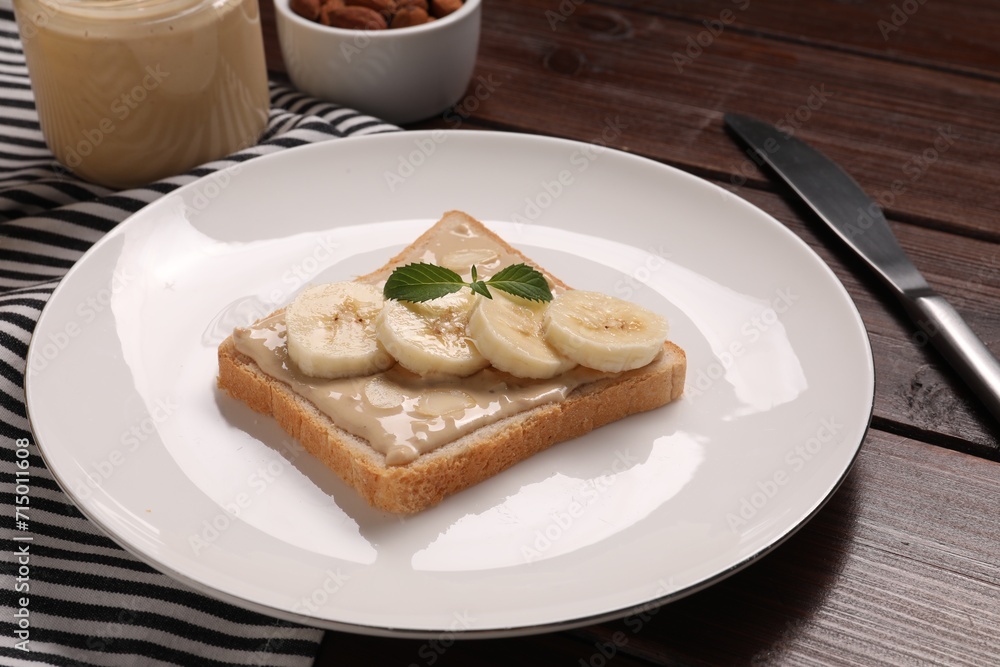 Toast with tasty nut butter and banana slices on wooden table, closeup Toast with tasty nut butter and banana slices on wooden table, closeup