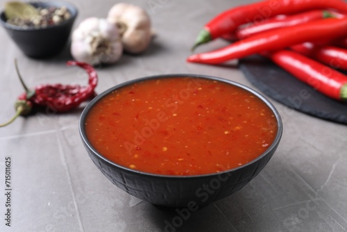 Spicy chili sauce in bowl on grey table