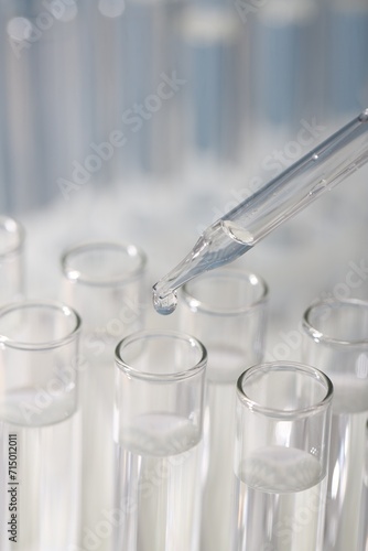 Laboratory analysis. Dripping liquid from pipette into glass test tube on blurred background, closeup